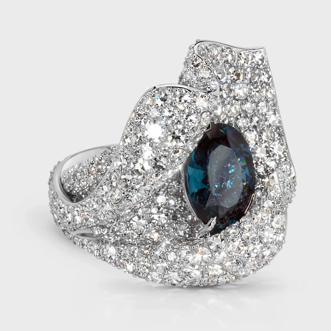 Azure white gold ring by ValeOro with an oval blue spinel framed by pavé diamonds in a wavy setting, three-quarter view
