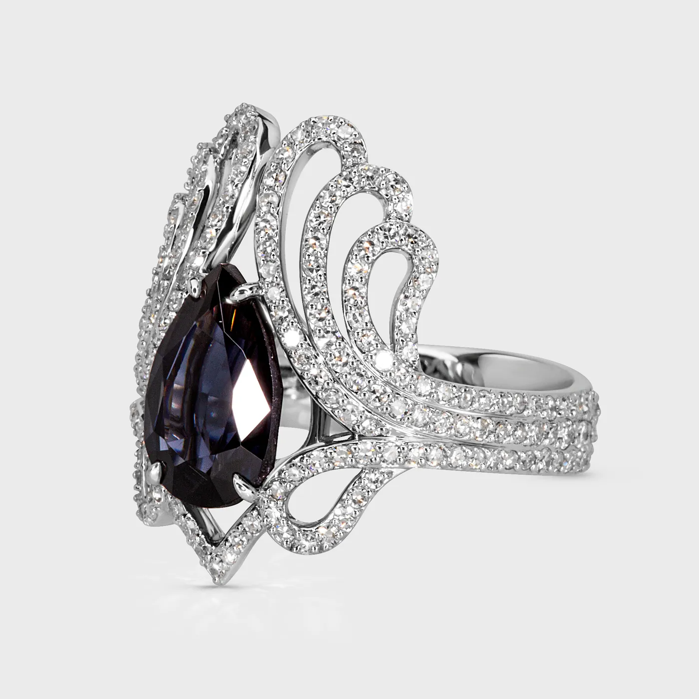 Regalia white gold ring by ValeOro with a pear-cut blue spinel and curling diamond scrollwork, side view