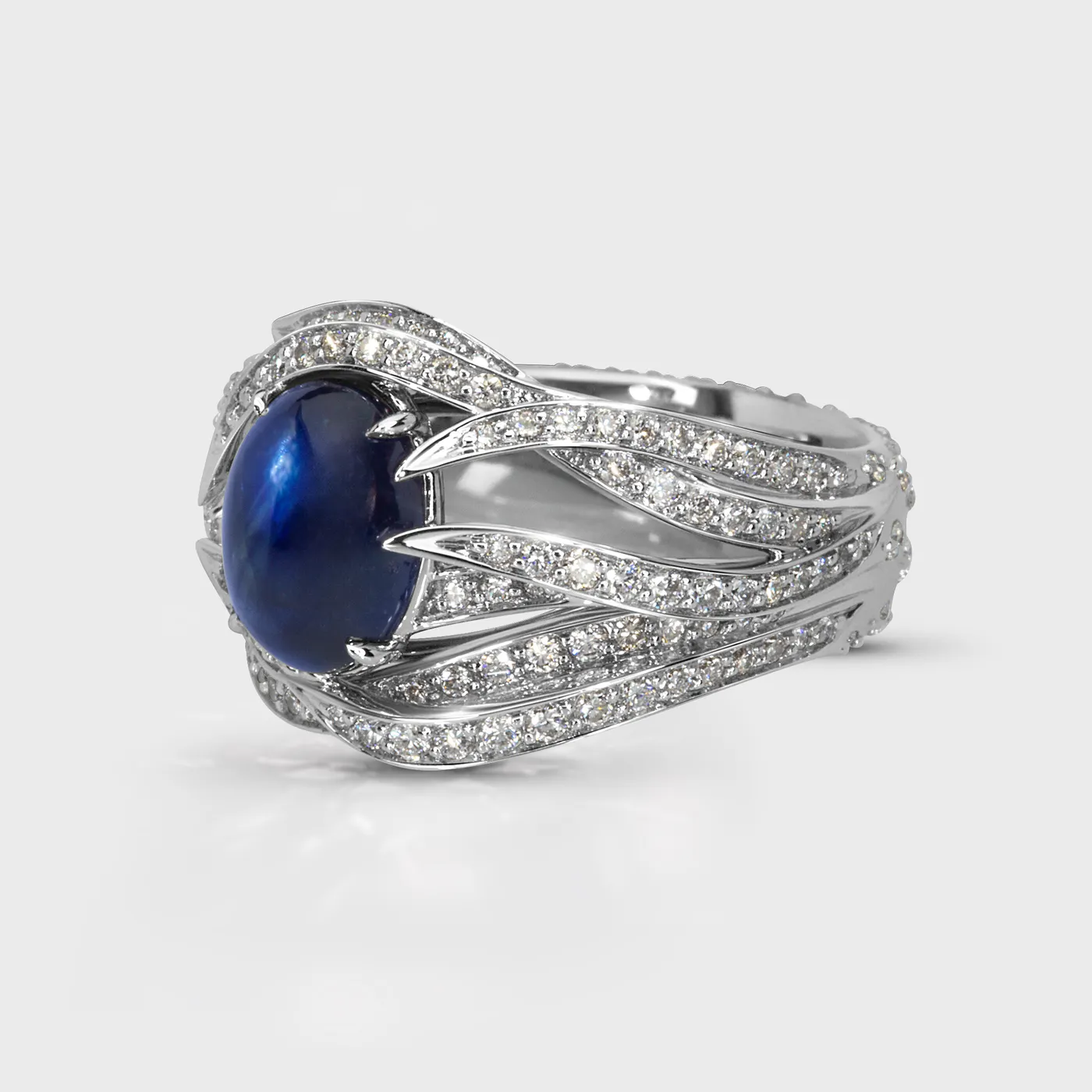 Astraea white gold ring by ValeOro with a blue cabochon sapphire and diamond-set flowing lines, side view