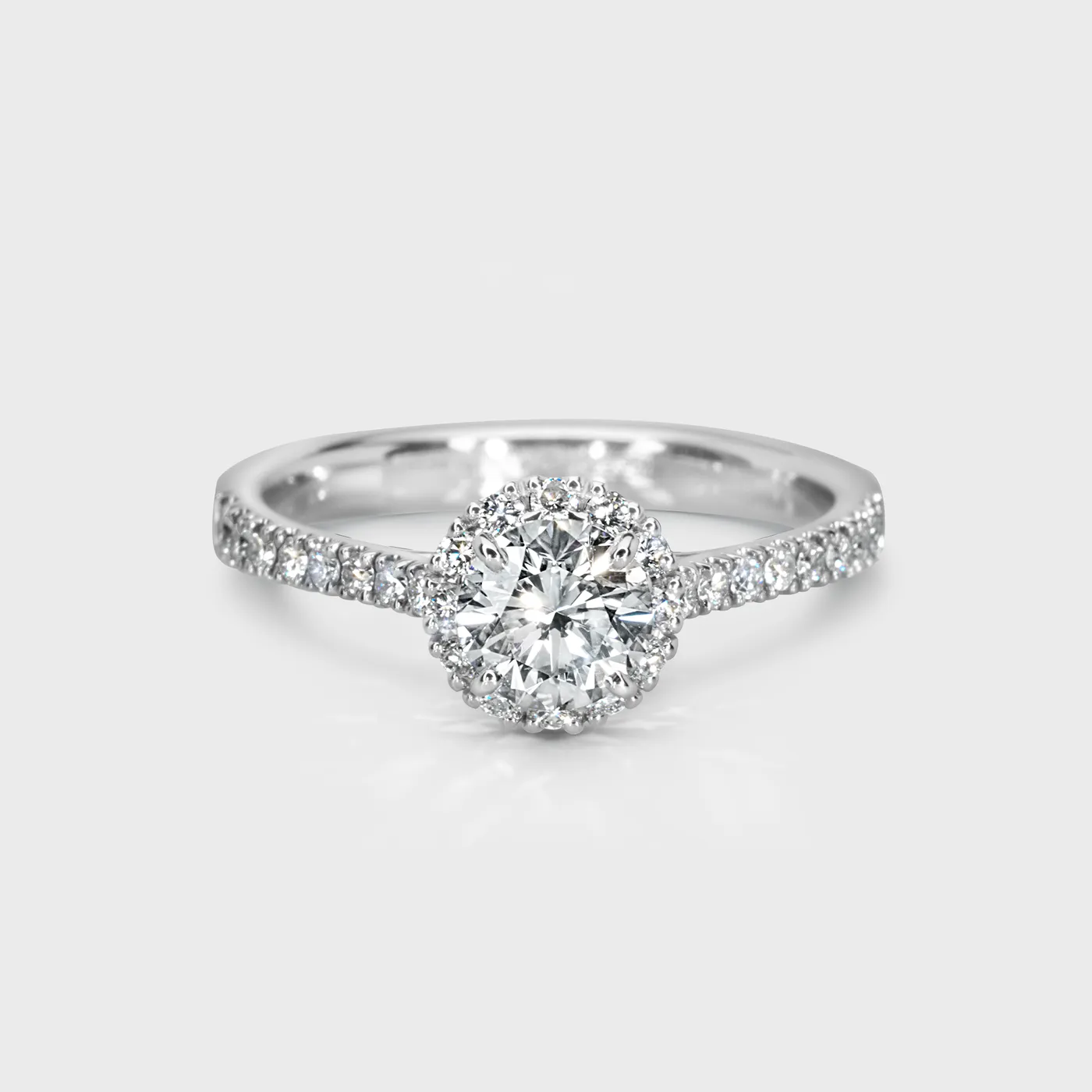 Aurora white gold ring by ValeOro with a round diamond in a halo of smaller diamonds and a pavé band, front view
