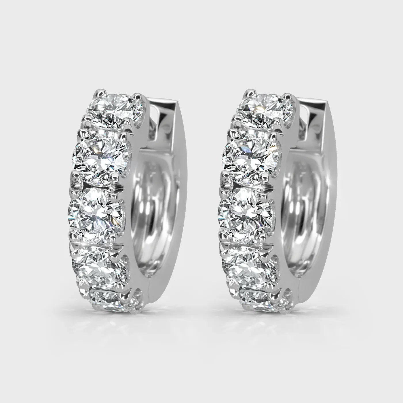 Gloss white gold hoop earrings by ValeOro set with round diamonds along the front, three-quarter view