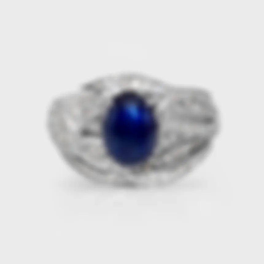 Astraea white gold ring by ValeOro with an oval blue cabochon sapphire in an openwork diamond setting, front view